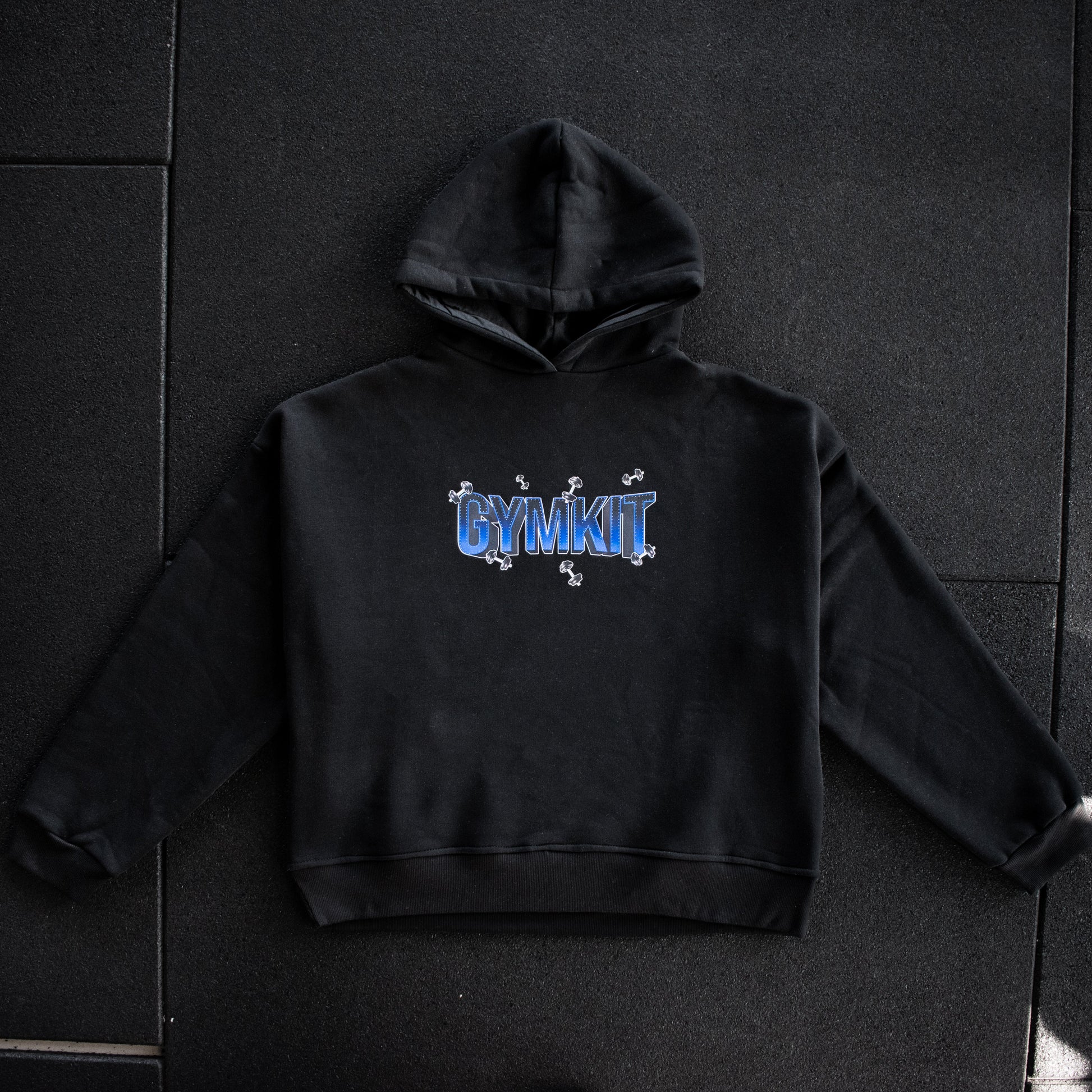 Black hoodie with 'GYMKIT' text on a dark tiled floor