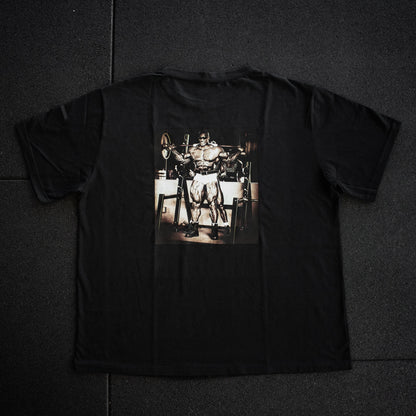 Black t-shirt with a graphic of a person lifting weights on a dark surface